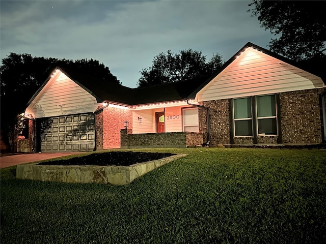 view of front of house featuring brick siding, an attached garage, driveway, and a front yard
