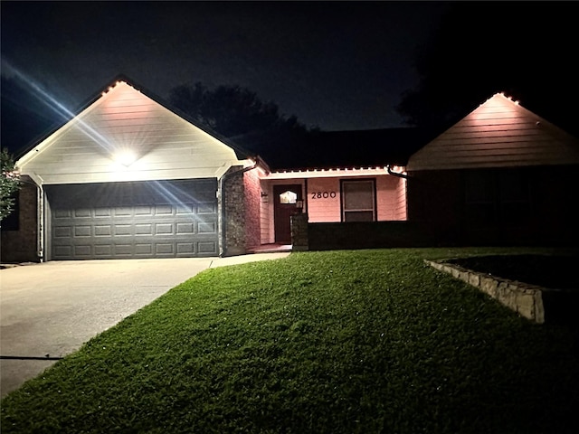 single story home with a yard, an attached garage, and driveway
