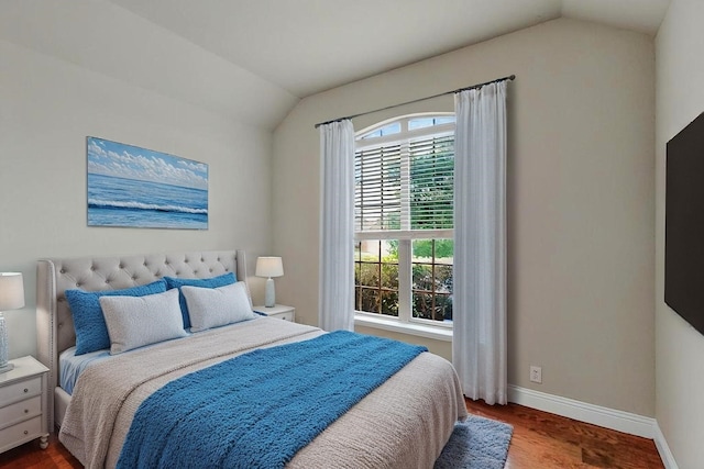 bedroom featuring baseboards, wood finished floors, and lofted ceiling