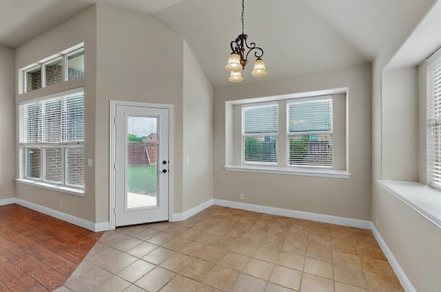interior space featuring baseboards, a chandelier, and lofted ceiling