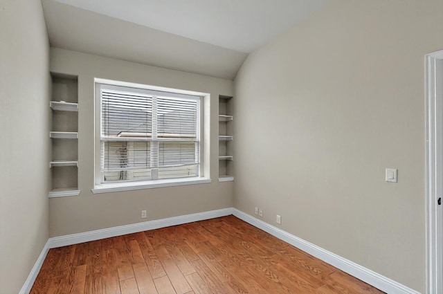 unfurnished room with baseboards, light wood-type flooring, and built in shelves