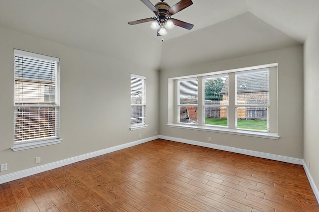 spare room featuring baseboards, a ceiling fan, wood finished floors, and a wealth of natural light