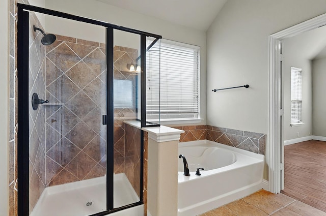 bathroom featuring baseboards, a shower stall, a healthy amount of sunlight, and a bath