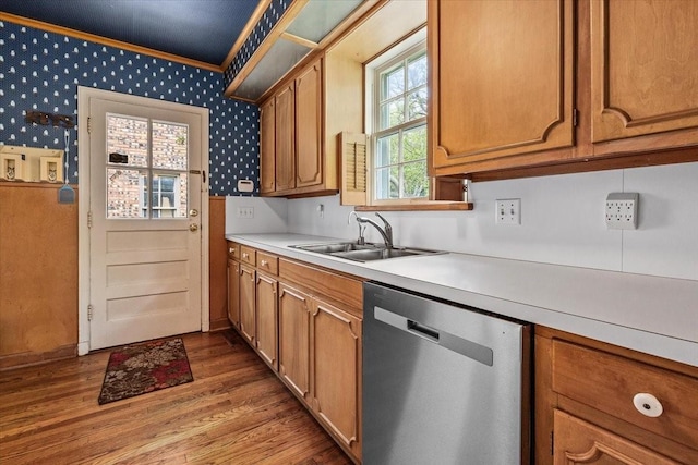 kitchen featuring ornamental molding, wood finished floors, light countertops, a sink, and dishwasher