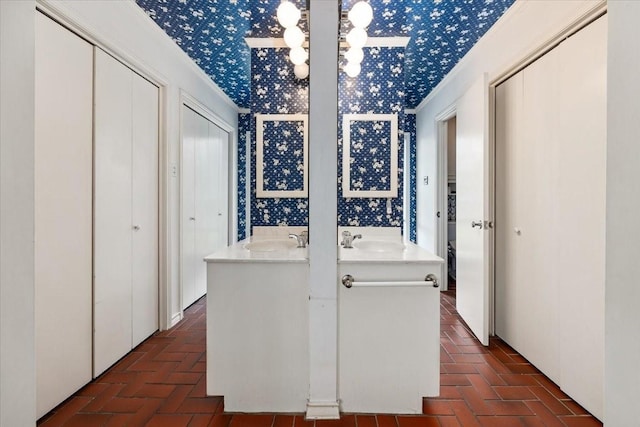 interior space featuring a sink, brick floor, and wallpapered walls