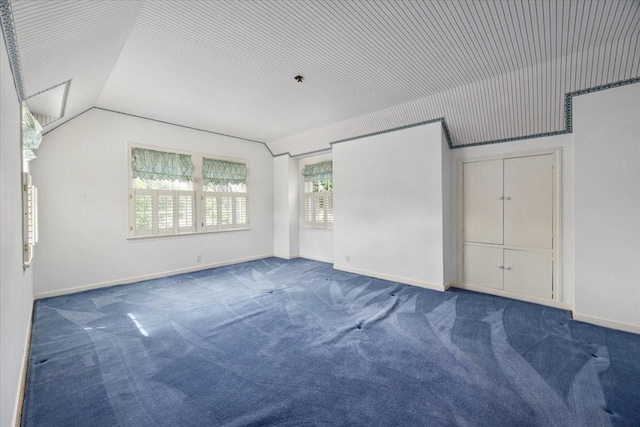 carpeted empty room with baseboards and lofted ceiling