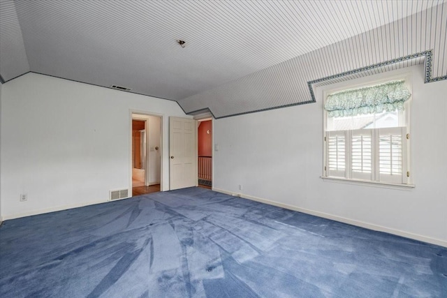 unfurnished room with carpet, vaulted ceiling, and visible vents