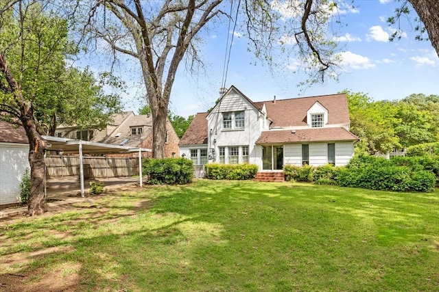 rear view of property with a lawn and fence