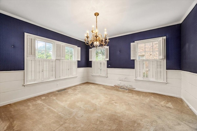 empty room with crown molding, plenty of natural light, and a chandelier