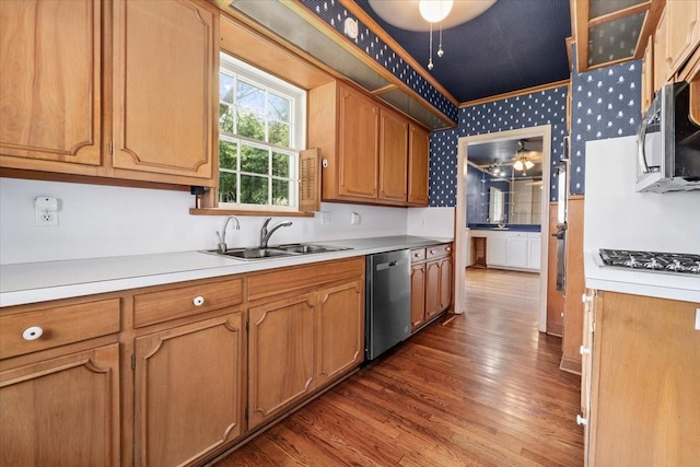 kitchen featuring dark wood-style flooring, light countertops, brown cabinets, a sink, and stainless steel appliances