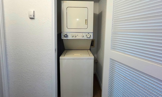 washroom with laundry area, stacked washing maching and dryer, and a textured wall