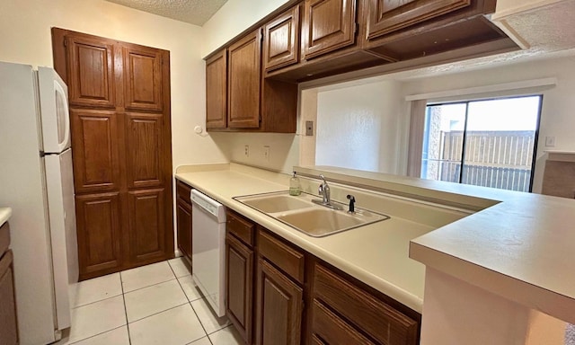 kitchen featuring white appliances, light tile patterned flooring, a sink, and light countertops