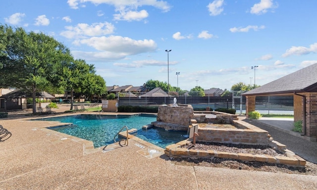 view of swimming pool with fence, a patio, and a pool with connected hot tub