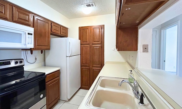 kitchen with a textured ceiling, visible vents, a sink, light countertops, and white appliances