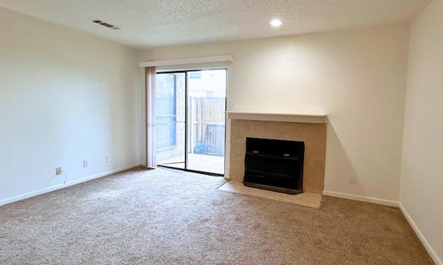 unfurnished living room featuring a fireplace with flush hearth, baseboards, carpet, and visible vents
