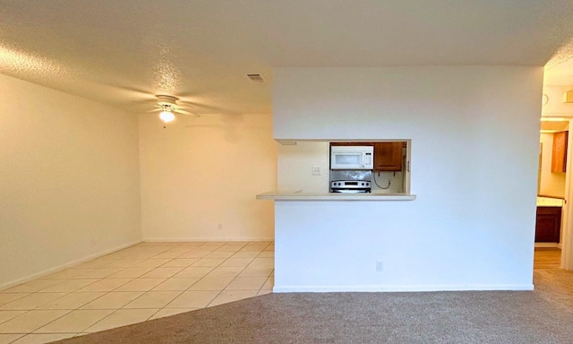 kitchen featuring a ceiling fan, visible vents, range, light tile patterned floors, and white microwave