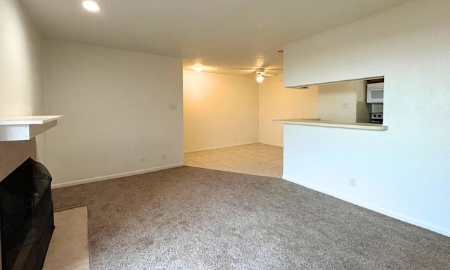 unfurnished living room featuring light carpet, baseboards, ceiling fan, recessed lighting, and light tile patterned floors