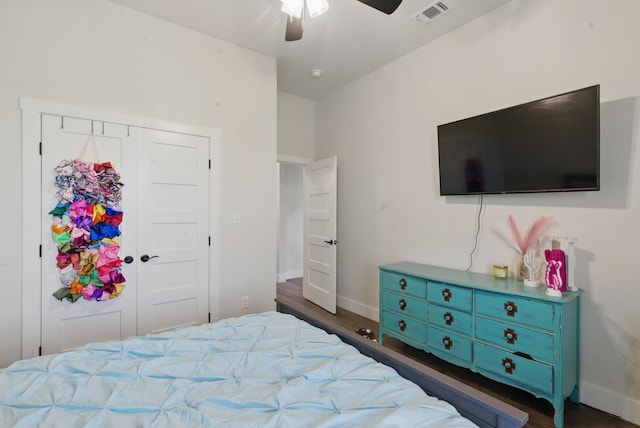bedroom featuring a ceiling fan, visible vents, wood finished floors, baseboards, and a closet