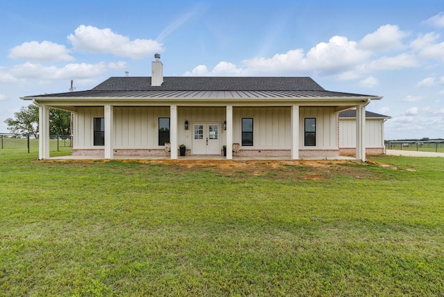 rear view of property featuring a lawn, board and batten siding, fence, and a chimney