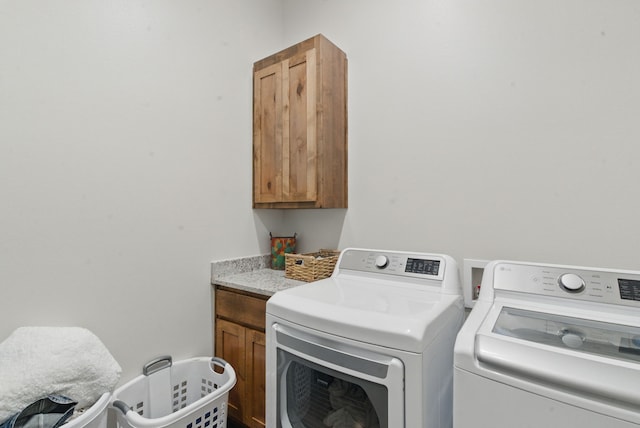 clothes washing area with washing machine and dryer and cabinet space