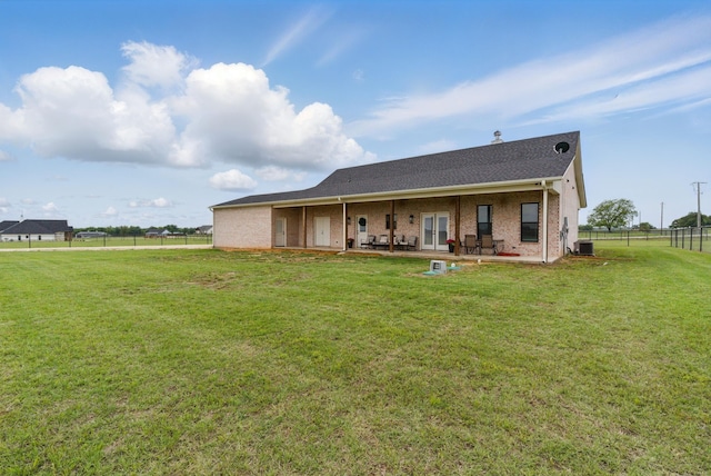 rear view of property with a lawn, a patio area, central air condition unit, and fence