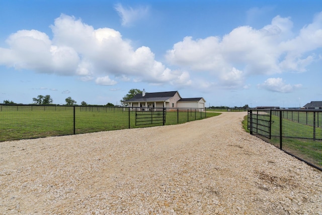 view of road with a gated entry, a rural view, and driveway