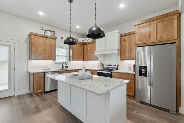 kitchen with dark wood-style flooring, appliances with stainless steel finishes, a sink, a center island, and backsplash