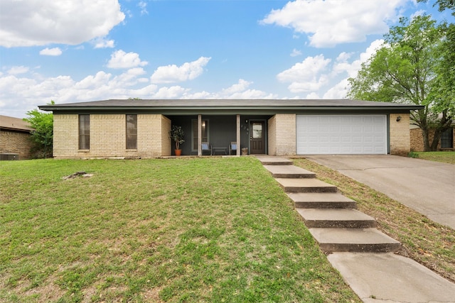 single story home with concrete driveway, brick siding, an attached garage, and a front lawn