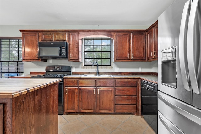 kitchen featuring plenty of natural light, a sink, light tile patterned floors, and black appliances