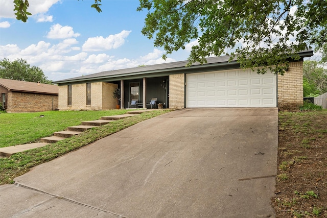 view of front of property with an attached garage, concrete driveway, a front lawn, and brick siding