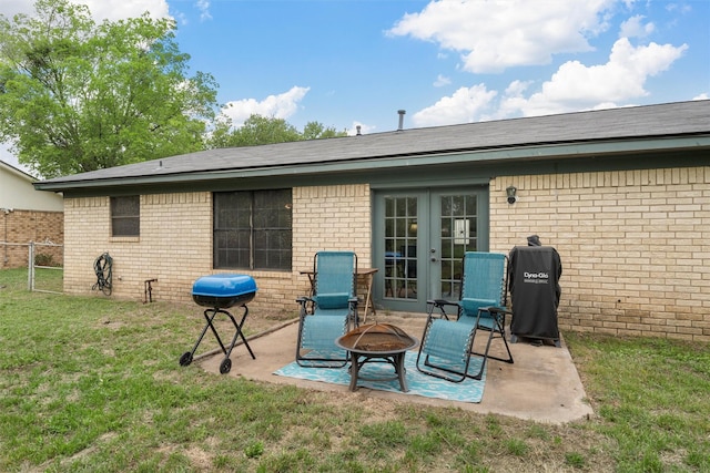 back of property with a patio, french doors, brick siding, a lawn, and an outdoor fire pit