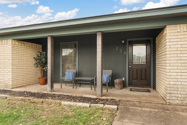 doorway to property with a porch and brick siding