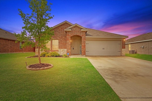view of front of home with driveway, a garage, brick siding, cooling unit, and a yard