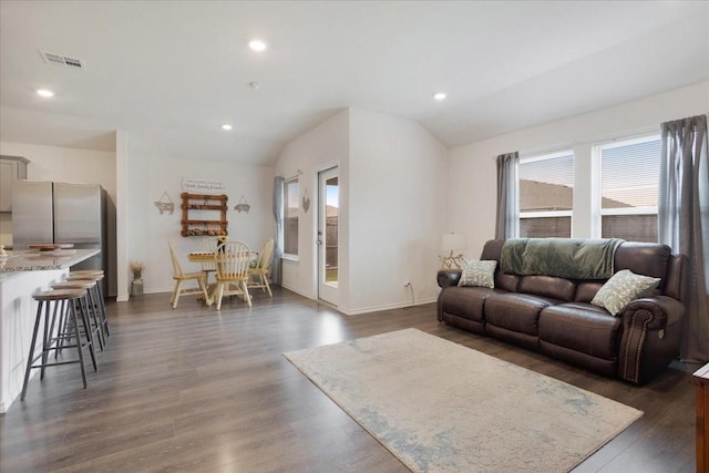 living room featuring dark wood-style flooring, baseboards, visible vents, and lofted ceiling