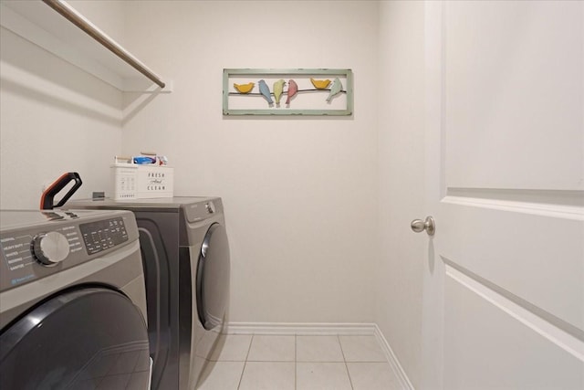 laundry room with laundry area, washer and clothes dryer, baseboards, and light tile patterned flooring