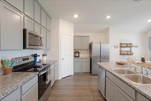 kitchen with dark wood-type flooring, recessed lighting, gray cabinets, a sink, and stainless steel appliances