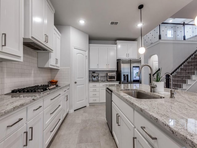 kitchen with decorative backsplash, white cabinetry, arched walkways, a sink, and appliances with stainless steel finishes