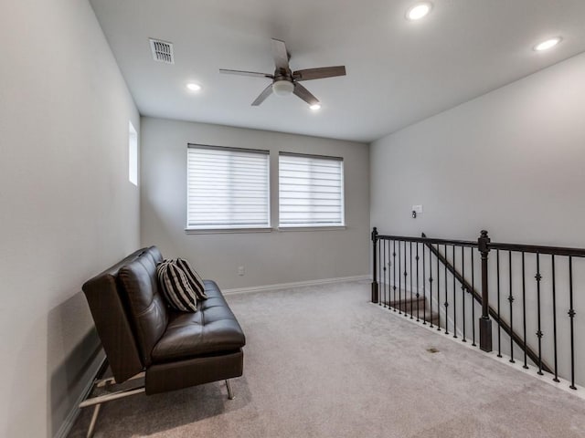 living area featuring carpet flooring, a ceiling fan, visible vents, and a wealth of natural light