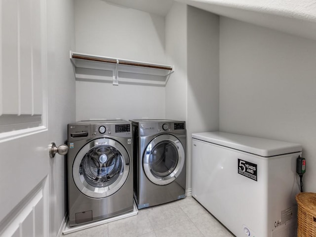 laundry area with laundry area, washer and clothes dryer, and light tile patterned floors