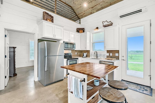 kitchen featuring finished concrete floors, appliances with stainless steel finishes, a sink, wooden ceiling, and an AC wall unit