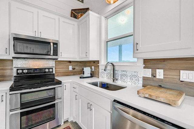 kitchen with white cabinetry, appliances with stainless steel finishes, a sink, and tasteful backsplash