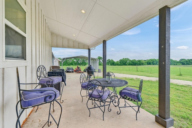 view of patio / terrace featuring a carport, outdoor dining area, and a rural view
