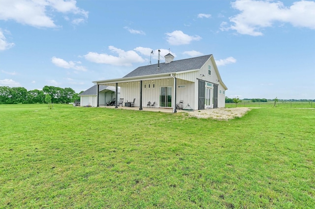 rear view of house with a patio, board and batten siding, a yard, and a chimney