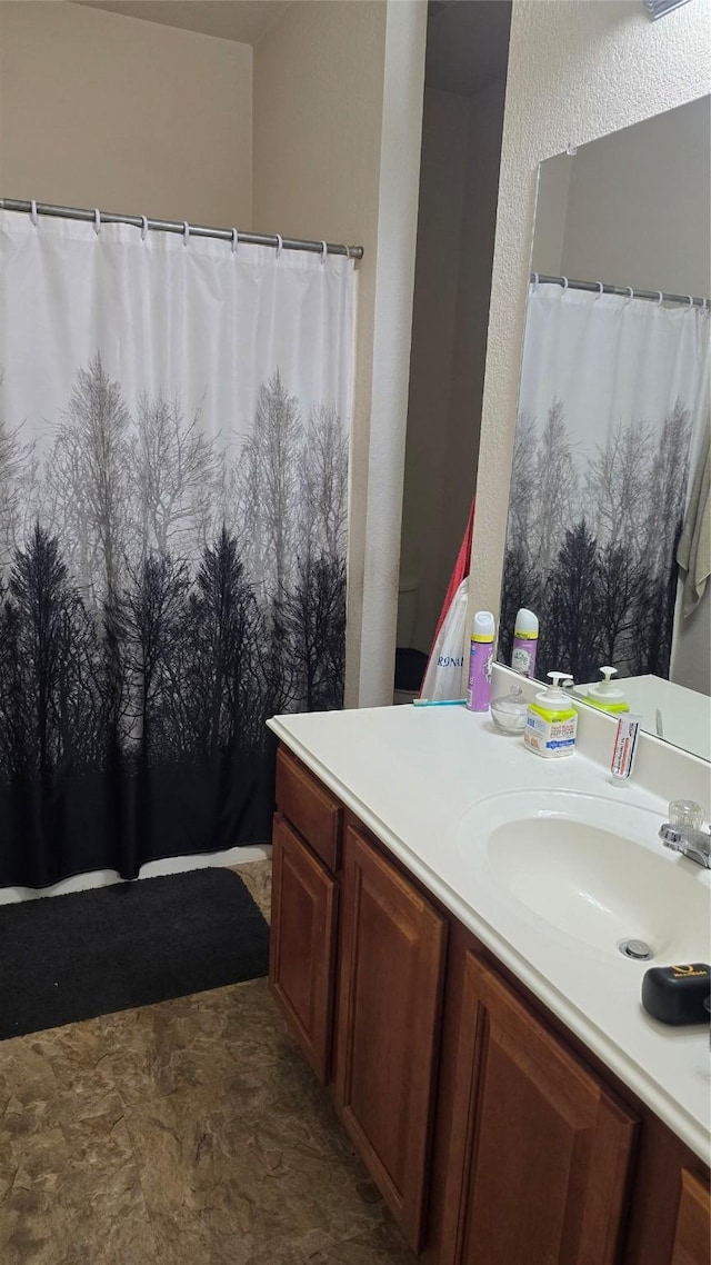 bathroom with a shower with curtain, a textured wall, and vanity