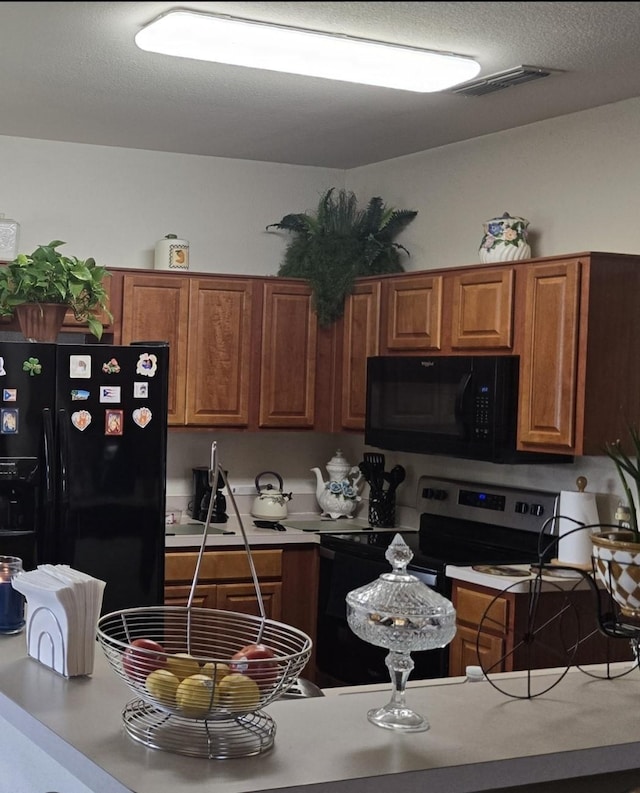 kitchen featuring brown cabinets, visible vents, black appliances, and light countertops