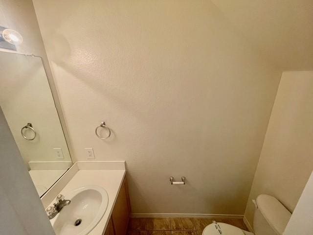 half bath featuring vanity, baseboards, and toilet