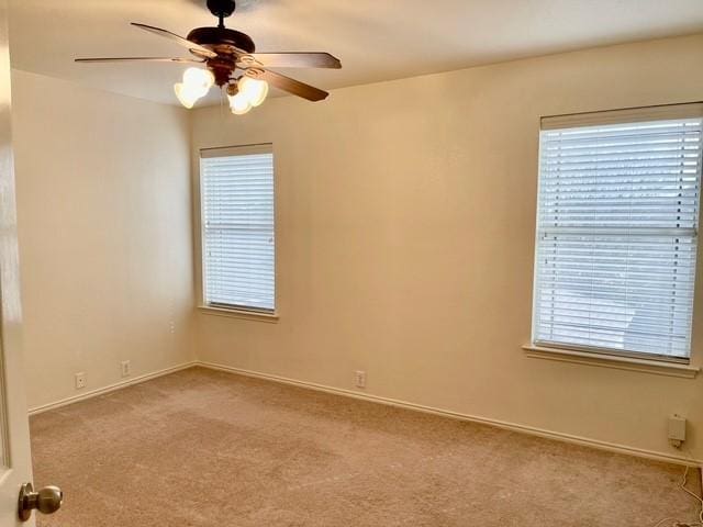 carpeted spare room with baseboards, a ceiling fan, and a healthy amount of sunlight