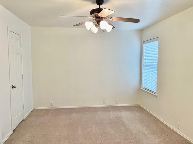 empty room featuring a ceiling fan, baseboards, and light colored carpet