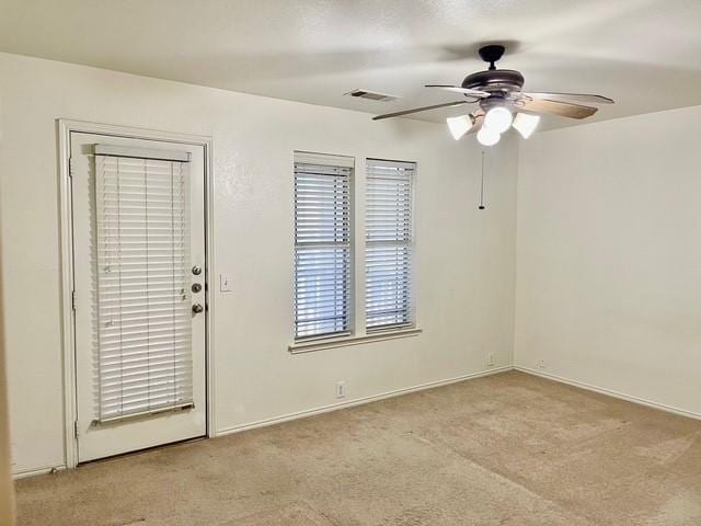 carpeted spare room with a ceiling fan, baseboards, and visible vents