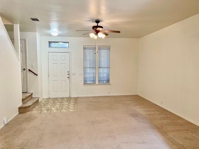 entrance foyer featuring visible vents, baseboards, stairway, light colored carpet, and a ceiling fan